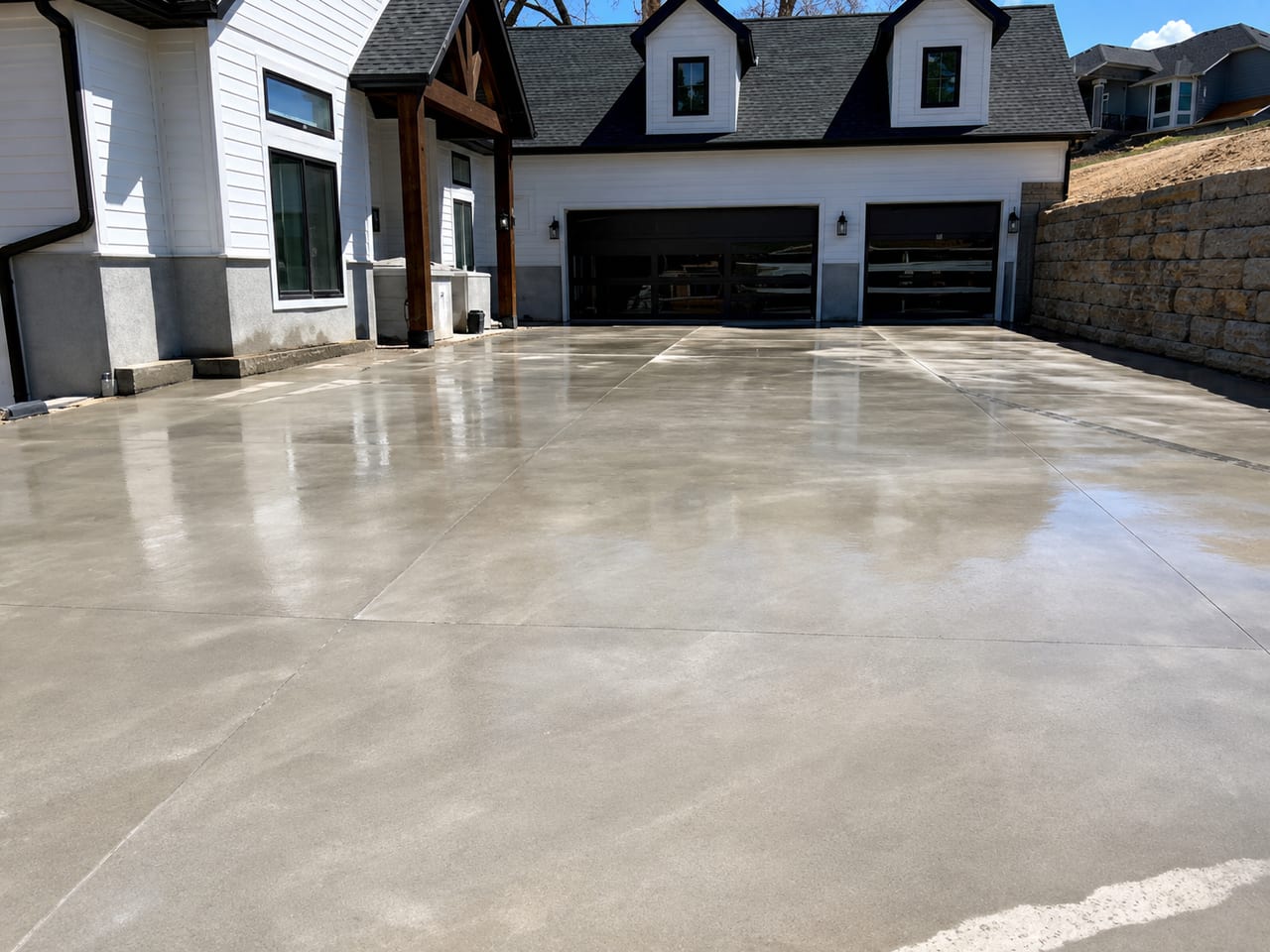 Wide polished concrete driveway leading to a three-car garage at a modern home